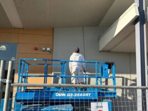 Commercial painter on a lift working on an exterior wall for a painting project estimate.