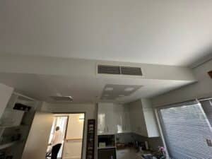 Modern kitchen with air conditioning vent and ceiling patchwork, showing how different types of paint can be applied in renovation.